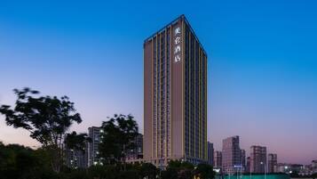 A tall hotel building with a modern design, featuring a prominent vertical stripe pattern and illuminated signage.