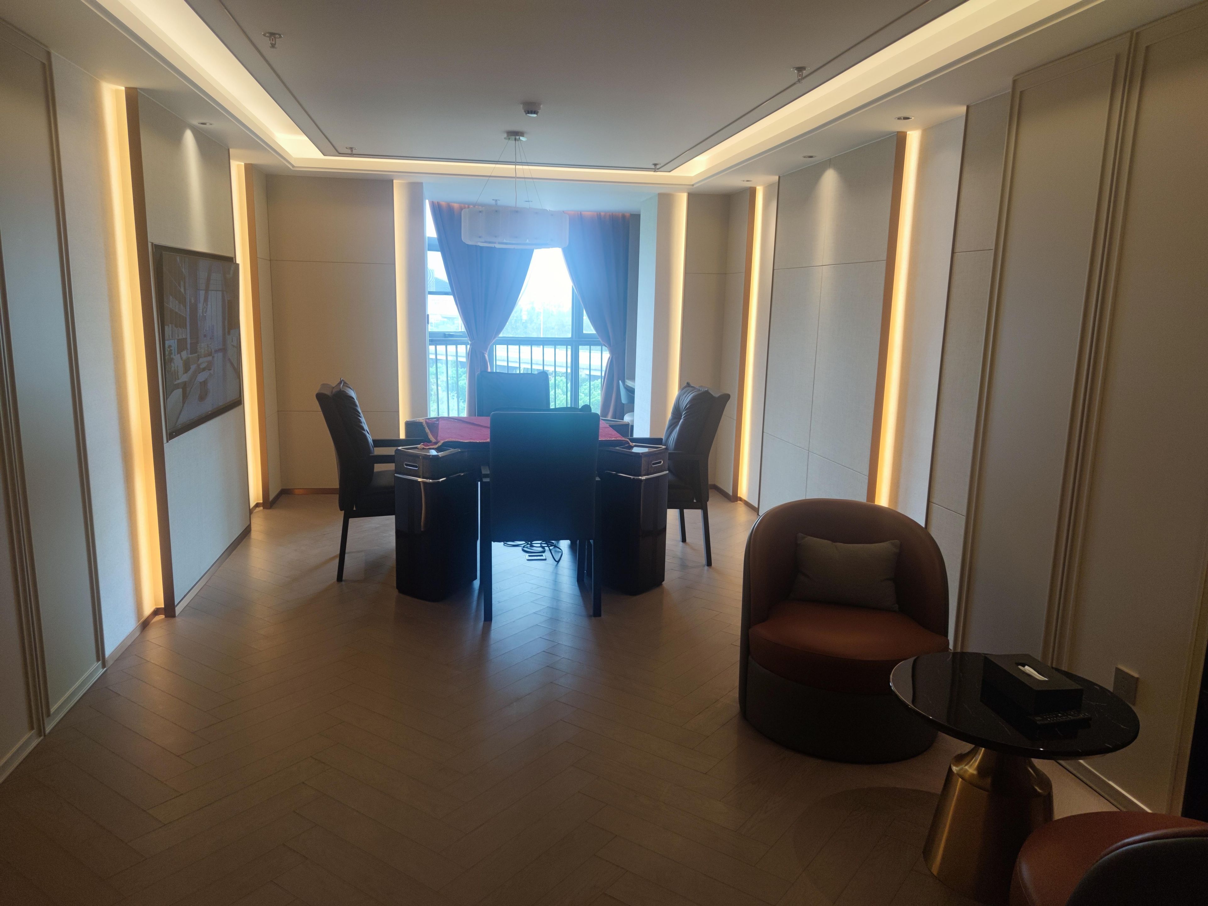 Una habitación de hotel moderna con comedor, sofá y una pequeña mesa con un control remoto.