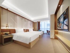 Une chambre d’hôtel moderne dotée d’un grand lit, de tables de chevet, d’un bureau et d’un coin salon.