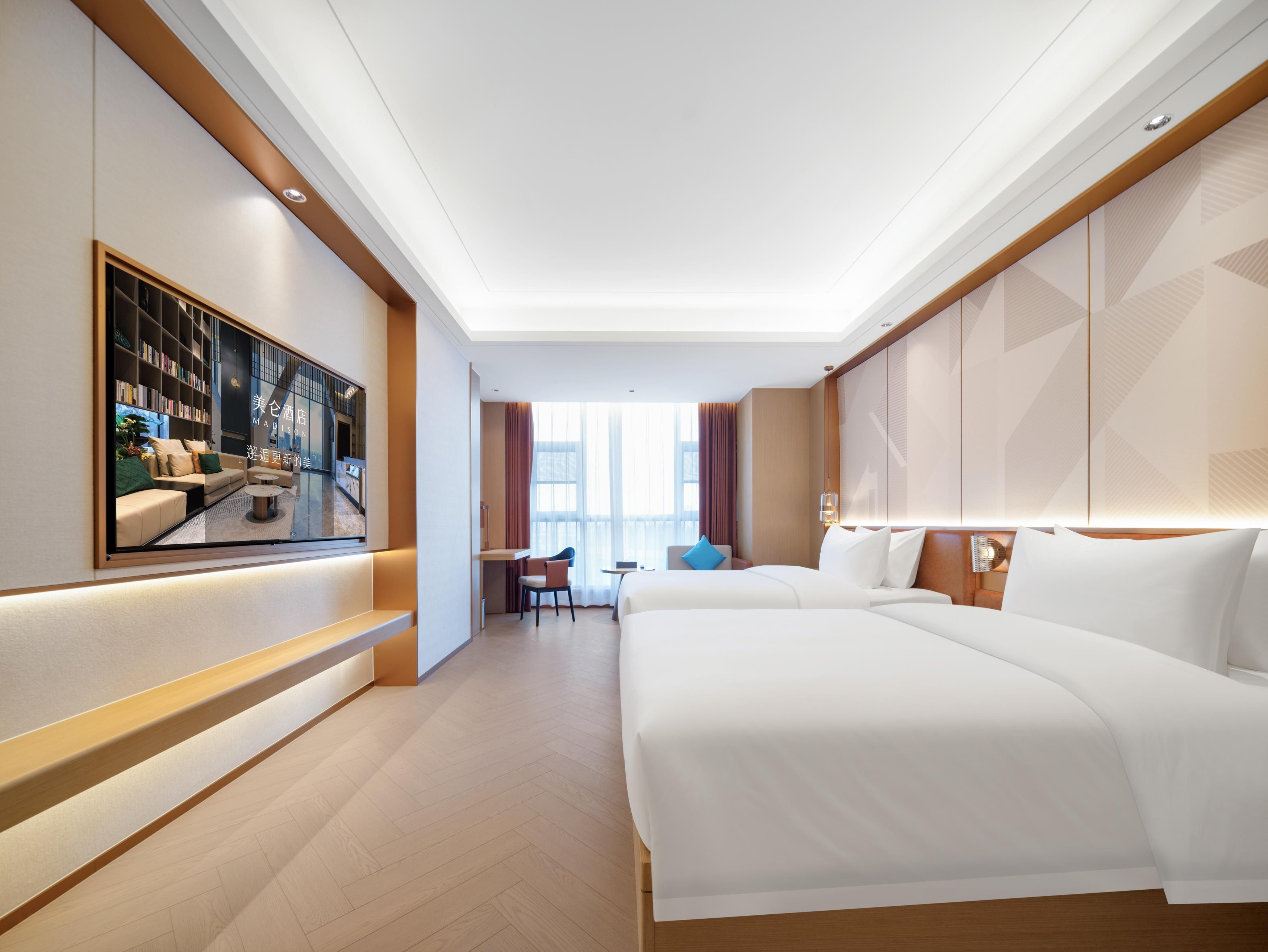 Una habitación de hotel con una cama grande, un escritorio, una silla y un televisor montado en la pared.