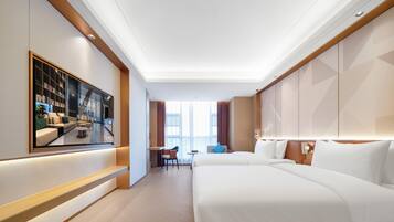 Una habitación de hotel con una cama grande, un escritorio, una silla y un televisor montado en la pared.