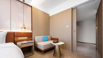 A modern hotel room with a bed, a sofa, a small table, and a wardrobe.
