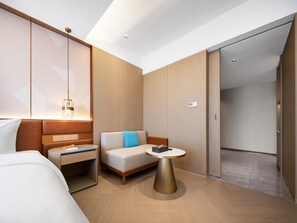 A modern hotel room with a bed, a sofa, a small table, and a wardrobe.