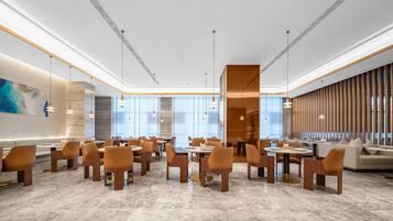 A spacious hotel lobby with a modern design, featuring marble flooring, contemporary furniture, and large windows allowing natural light.