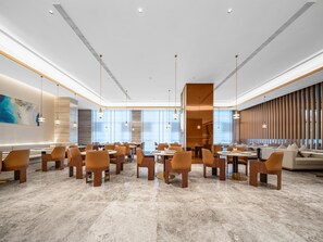 A spacious hotel lobby with a modern design, featuring marble flooring, contemporary furniture, and large windows allowing natural light.