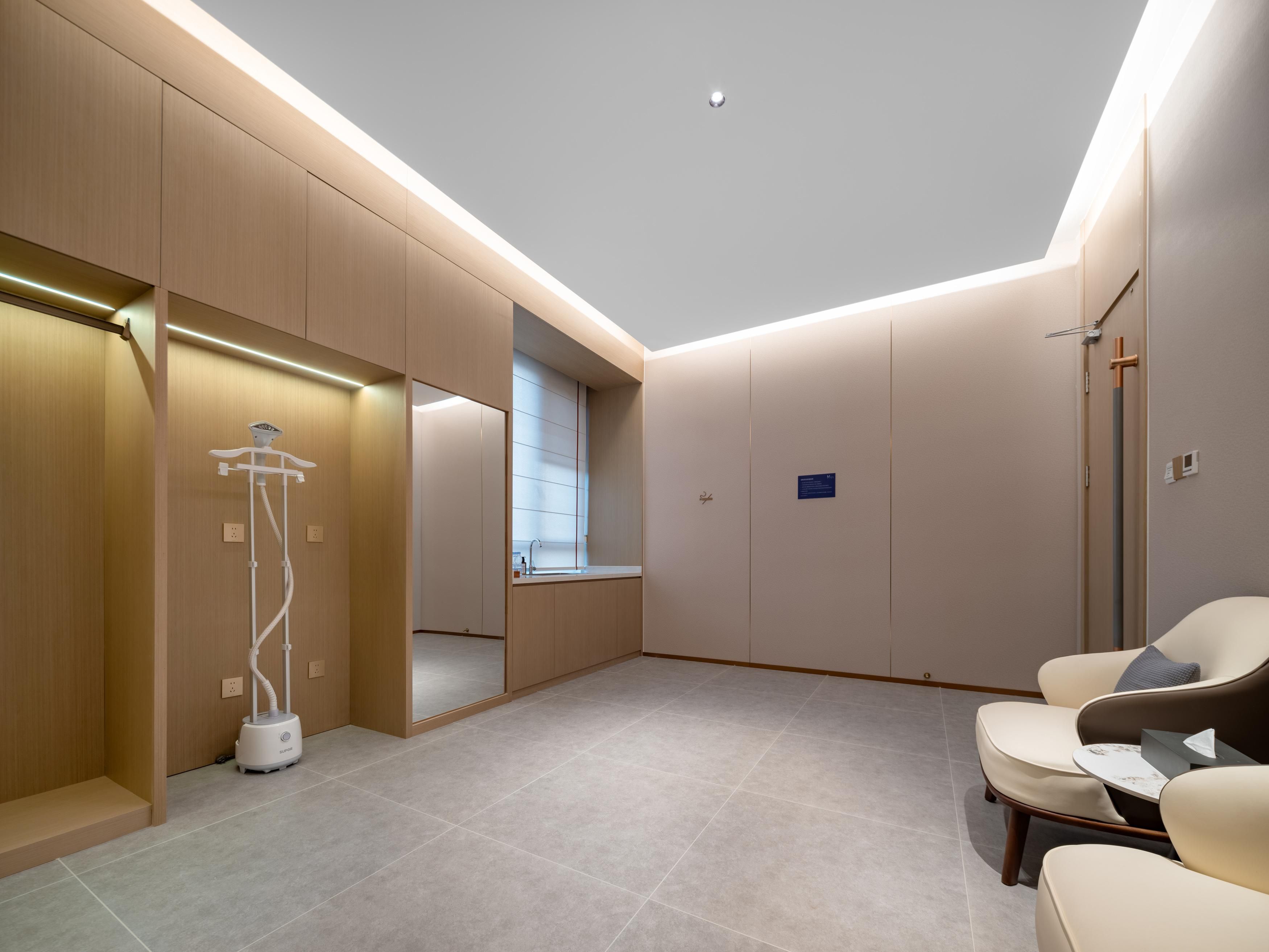 A modern hotel room with a walk-in closet, a large mirror, a seating area with a table, and a skylight.