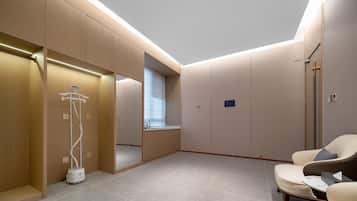Habitación de hotel moderna con vestidor, un espejo grande, un área de descanso con mesa y un tragaluz.