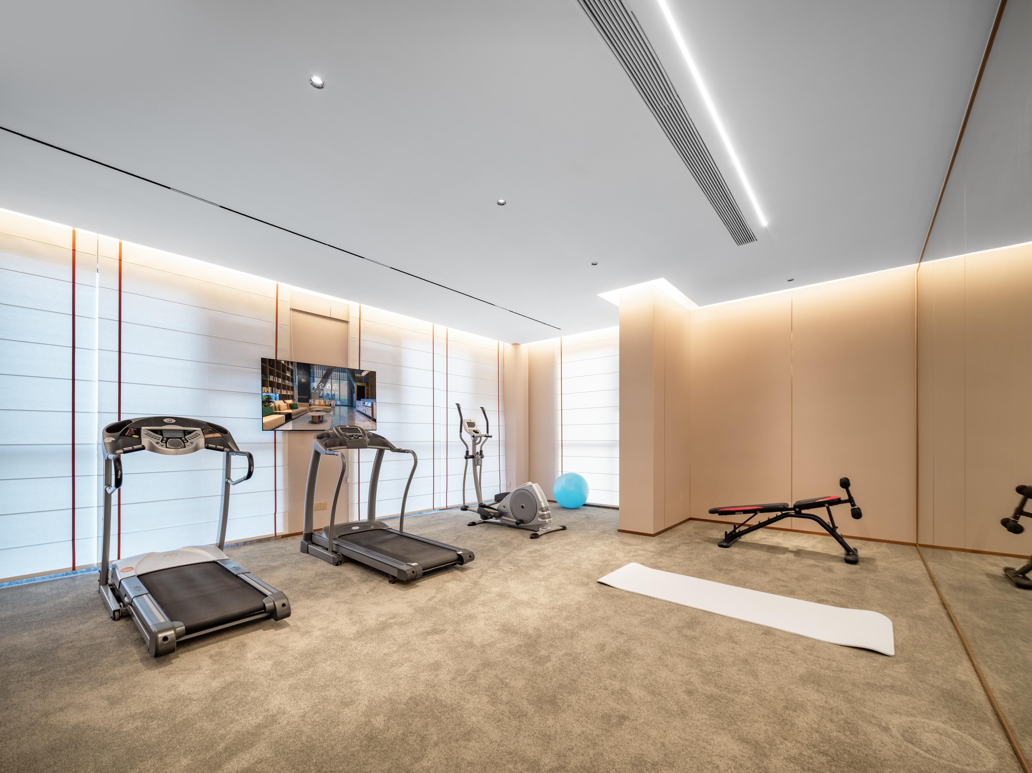 A modern home gym with treadmills, an elliptical, a stationary bike, and a yoga mat.