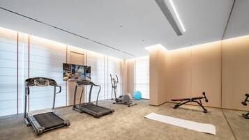 A modern home gym with treadmills, an elliptical, a stationary bike, and a yoga mat.
