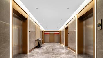 A modern elevator lobby with marble flooring, metallic elevator doors, and recessed lighting.