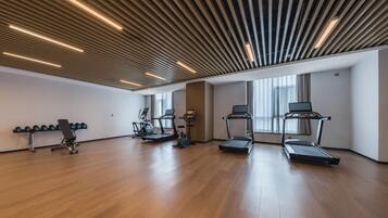 Un gimnasio amplio con cintas de correr, elípticas y una prensa de pesas.