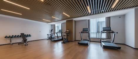 A spacious gym with treadmills, elliptical machines, and a bench press.
