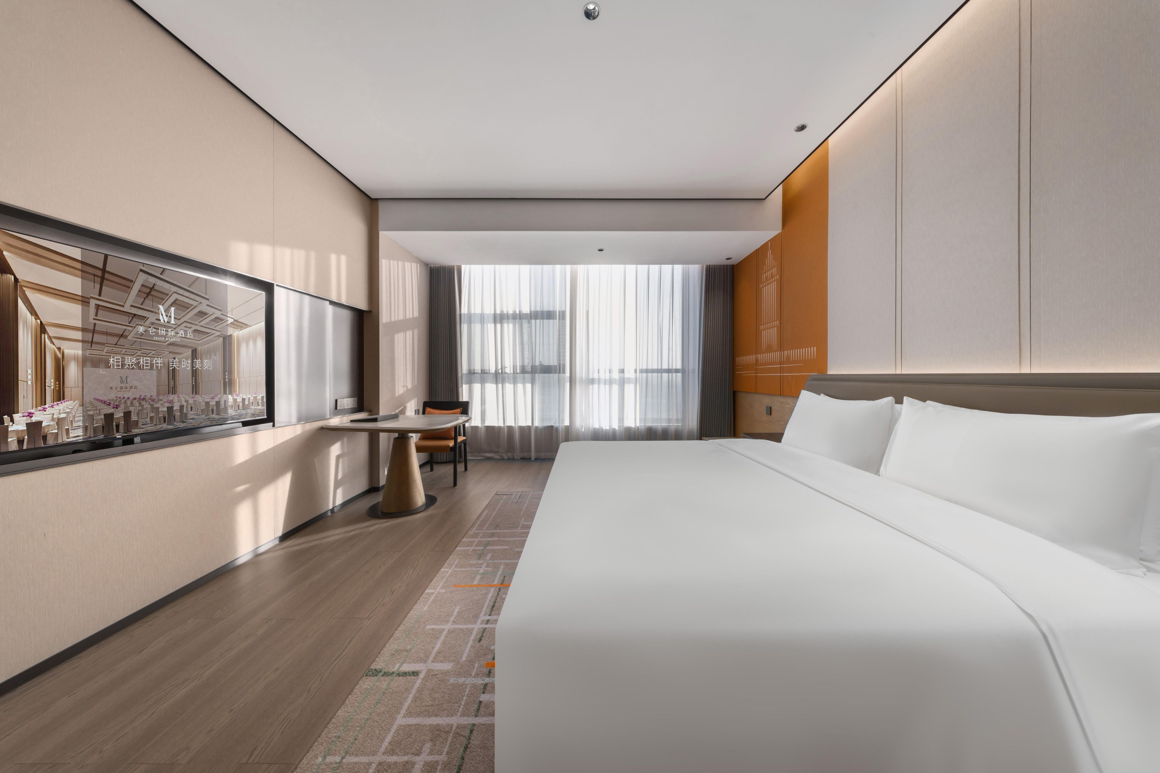Una habitación de hotel moderna con una cama grande, un escritorio y una ventana con cortinas translúcidas.