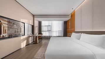 Una habitación de hotel moderna con una cama grande, un escritorio y una ventana con cortinas translúcidas.