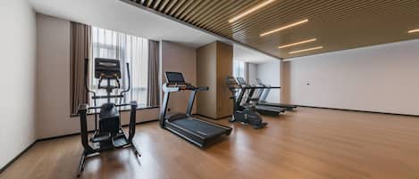 A modern gym with treadmills, elliptical machines, and a rowing machine.