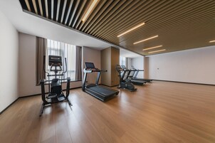 Un gimnasio moderno con cintas de correr, elípticas y una máquina de remo.