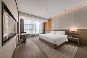 Una habitación de hotel moderna con una cama grande, un escritorio y vistas a la ciudad.