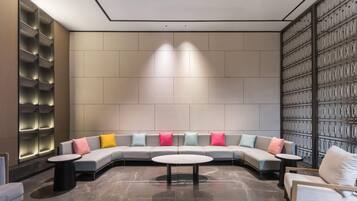 A modern lounge area with a curved sofa, round tables, and a patterned wall.