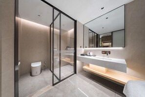 Un baño moderno con cabina de ducha de vidrio, un lavabo blanco y un espejo grande.