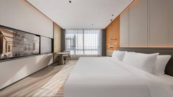 A modern hotel room with a large bed, a desk, and a window with curtains.