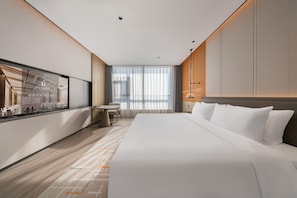 Une chambre d’hôtel moderne avec un grand lit, un bureau et une fenêtre avec des rideaux.