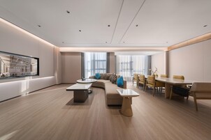 Una sala de estar moderna con un sofá curvo, una mesa de comedor y un ventanal grande.