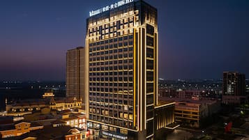 A high-rise hotel with illuminated signage, a central courtyard, and surrounding urban buildings.