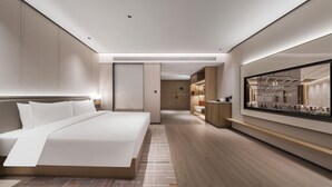Quarto de hotel moderno com uma cama grande, televisão de tela plana e piso de madeira.