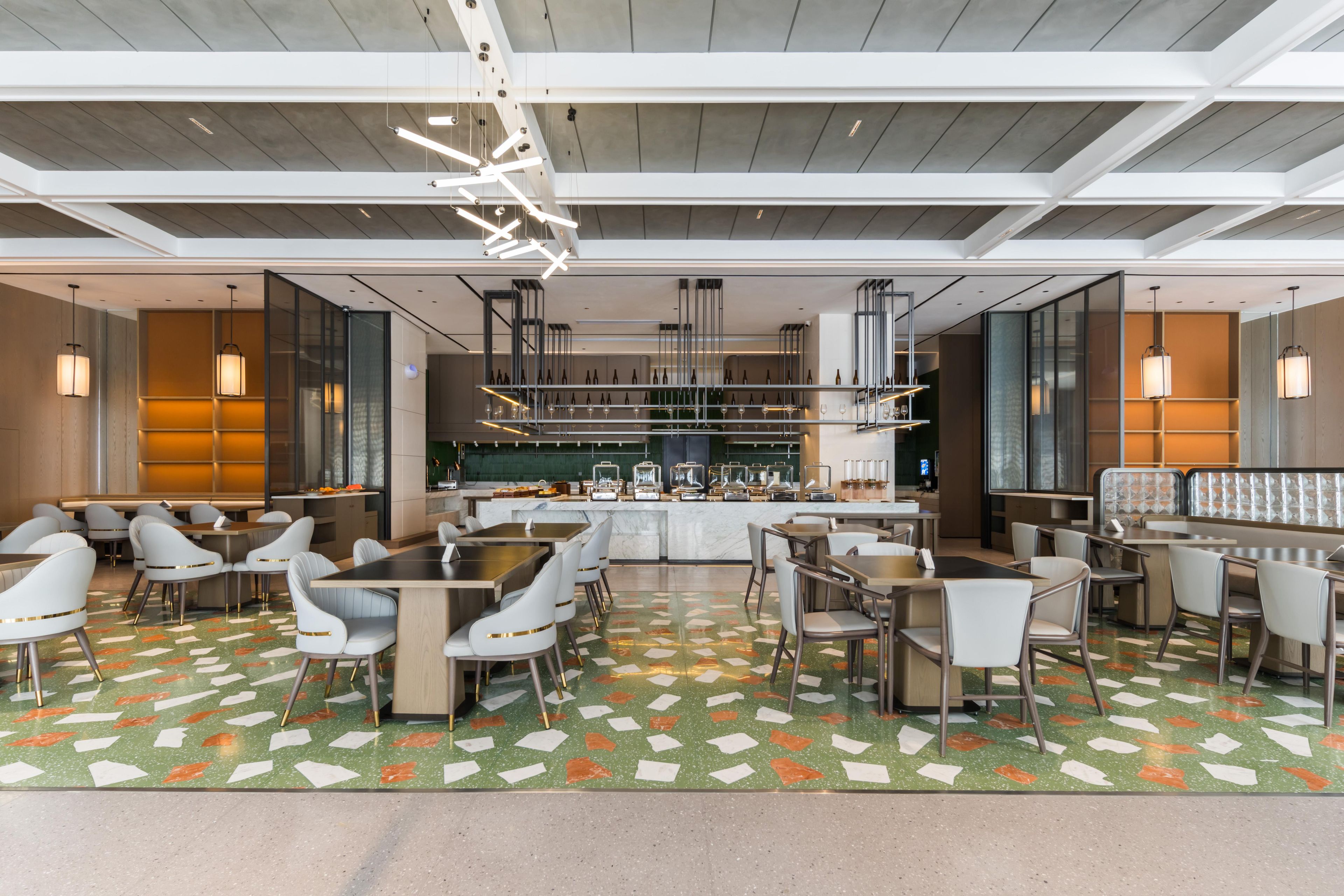 Un restaurante moderno con suelo estampado en verde, sillas blancas y una zona de bar.