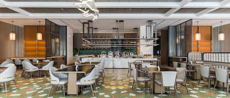 Un restaurante moderno con suelo estampado en verde, sillas blancas y una zona de bar.