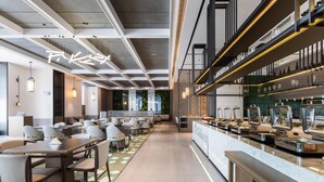 Um restaurante moderno com um balcão comprido, vários espaços de estar e teto alto com vigas aparentes.