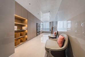 A modern laundry room with a sofa, baskets, and a large window. - Grand Madison Hotel Xiangyang Hexin Outlets (Xiangyang)