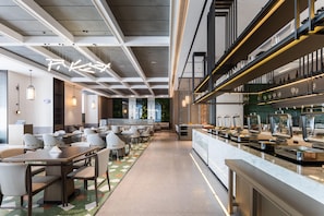 Un restaurante moderno con una barra larga, varias zonas de estar y un techo alto con vigas a la vista.