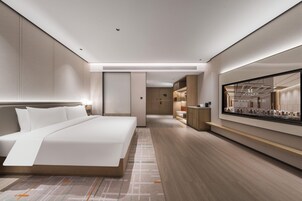 Una habitación de hotel moderna con una cama grande, un televisor de pantalla plana y piso de madera.