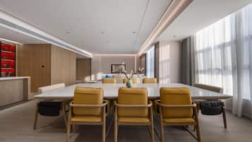 Un comedor moderno con una mesa grande y sillas amarillas, un armario de madera y vistas a la ciudad a través de ventanas amplias.