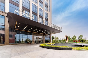 A modern building with a large glass facade and a sign that reads "GRAND MADISON". - Grand Madison Hotel Xiangyang Hexin Outlets (Xiangyang)