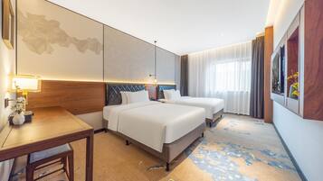 Ein Hotelzimmer mit zwei Betten, einem Schreibtisch, einer Lampe und einem großen, abstrakten Gemälde an der Wand.