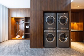 A laundry room with two stacked washing machines and a vacuum cleaner. - Madison Hotel Jinan Suncun Chunhui Road (Jinan)