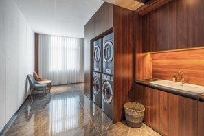 A modern bathroom with a marble floor, a wooden vanity with a sink, and a pair of wall-mounted washing machines. - Madison Hotel Jinan Suncun Chunhui Road (Jinan)