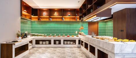 Una cocina moderna con una isla central, estanterías empotradas y salpicadero verde.