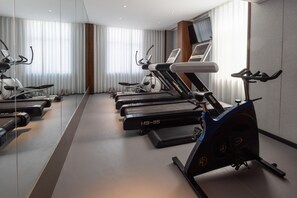 A modern gym with multiple treadmills and stationary bikes, large windows with curtains, and a minimalist design. - Madison Hotel Jinan Suncun Chunhui Road (Jinan)