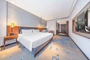 A modern hotel room with a large bed, bedside lamps, a small table, and a view of the hotel lobby. - Madison Hotel Jinan Suncun Chunhui Road (Jinan)