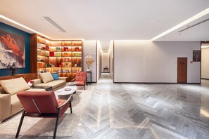 A modern hotel lobby with a seating area, a wall-mounted display, and a hallway leading to the entrance. - Madison Hotel Jinan Suncun Chunhui Road (Jinan)
