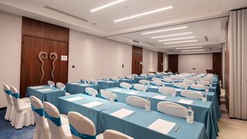 A conference room with rows of tables and chairs, equipped with nameplates and water bottles.