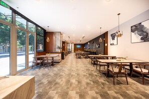 A spacious restaurant with long tables and chairs, large windows, and artwork on the walls. - Madison Hotel Jinan Suncun Chunhui Road (Jinan)