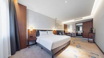 Una habitación de hotel moderna con una cama grande, mesitas de noche, un escritorio y un espejo.