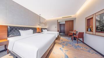 A hotel room with two beds, a small table, and a chair.