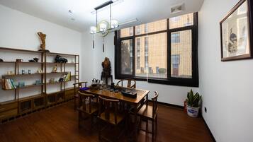 A dining area with a wooden table and chairs, surrounded by shelves with books and decorative items.