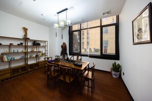 A dining area with a wooden table and chairs, surrounded by shelves with books and decorative items. - Madison Hotel Jinan Suncun Chunhui Road (Jinan)