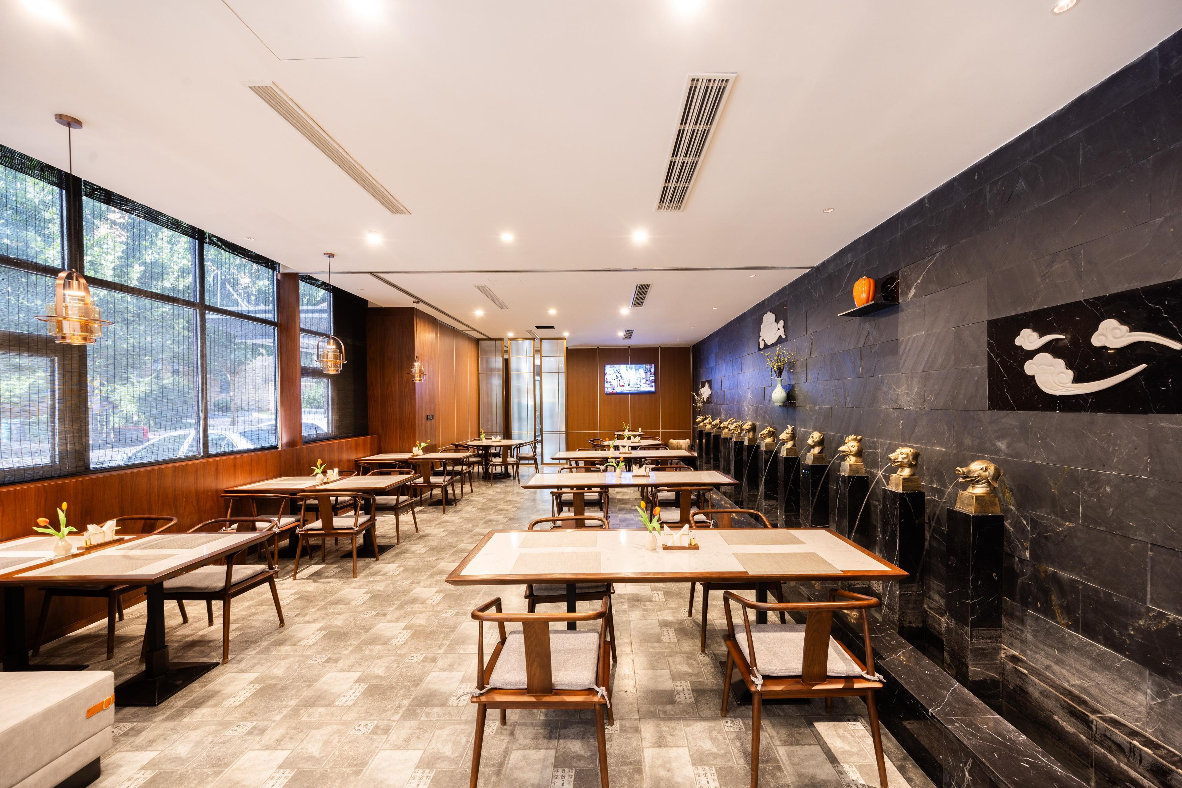 A restaurant with wooden tables and chairs, large windows, and decorative wall art.